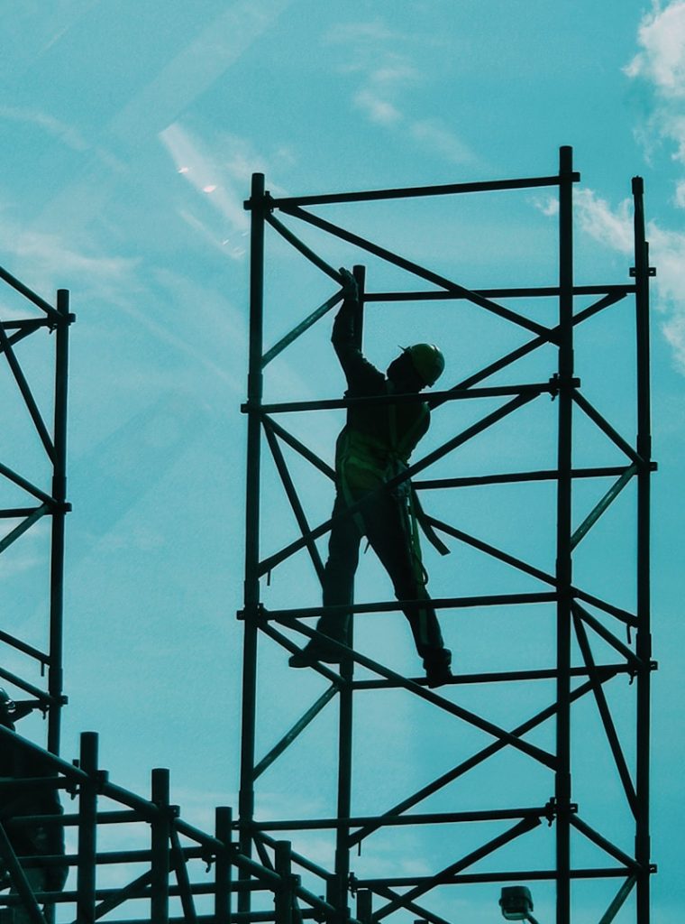 man in green t-shirt and green pants standing on black metal frame